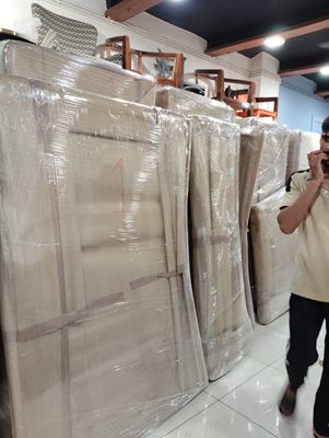 A crew member beside several tall wrapped panels lined up indoors.
