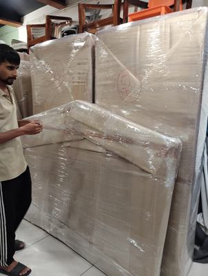 A crew member drawing stretch film around a large piece of furniture indoors.