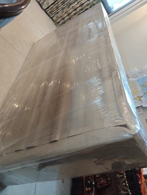 A close view of a large item wrapped in overlapping layers of film.