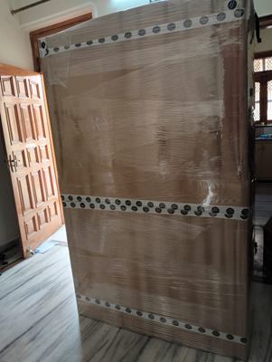 A large panel wrapped in corrugated sheet, standing against a doorway indoors.