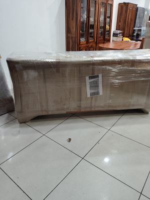 A long low sideboard wrapped and taped, resting on a tiled floor.