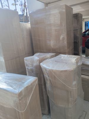 Wrapped furniture and taped cartons stacked together in a room, ready for loading.