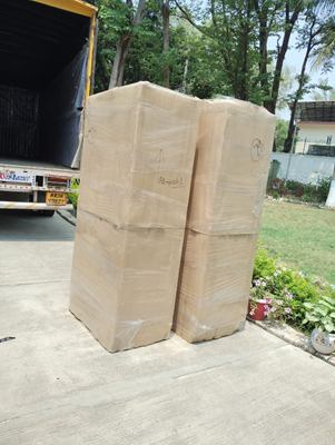 Two tall wrapped items standing beside the open tailgate of a transport vehicle.
