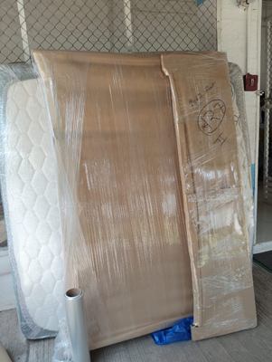 A rolled mattress beside wrapped flat panels, prepared together.