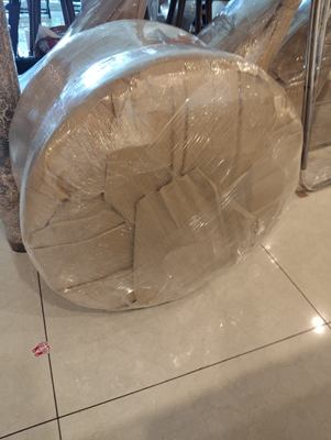 A round table top wrapped in corrugated sheet and stood on its edge.