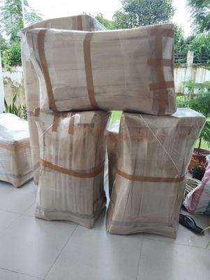 Soft items wrapped and strapped into blocks, stacked beside a window.