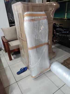 A tall item wrapped and strapped, standing upright in a living room.