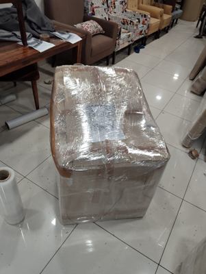 A single armchair wrapped in film, standing on a tiled floor.