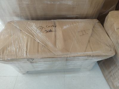 A low table wrapped in sheeting and labelled by hand on the top face.