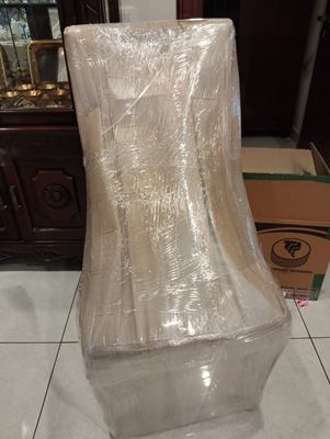 A wrapped chair standing in front of a carved wooden cabinet.