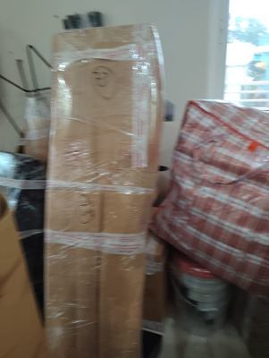 A wrapped item standing next to goods packed into a woven bag.