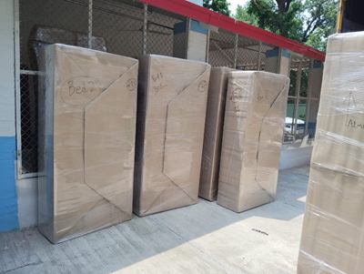 Several tall wrapped items lined up against a railing outside a house.