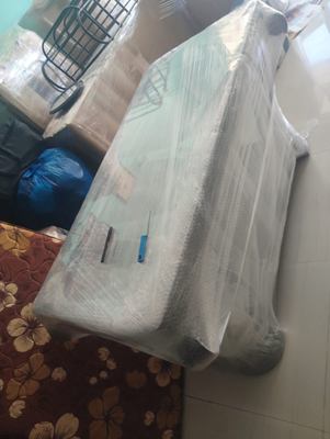 A mattress wrapped in plastic sheeting, laid flat on a carpeted floor.