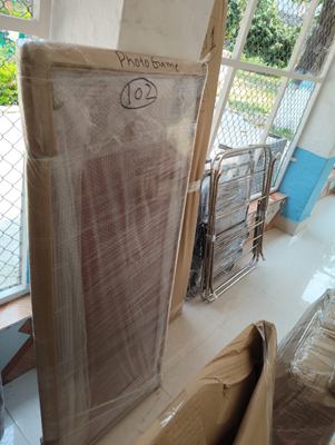 A wrapped panel standing beside a metal gate, labelled by hand.