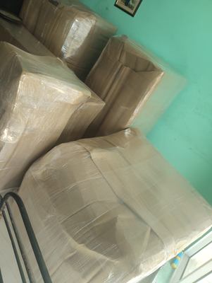 A sofa and two armchairs wrapped in corrugated sheet and stretch film, stacked ready to move.