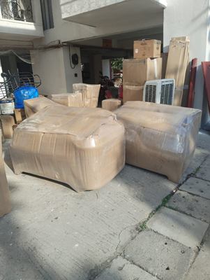 A wrapped sofa and matching ottoman standing in a covered parking area.