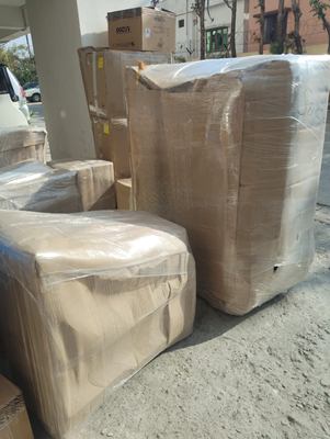 A wrapped sofa and other packed furniture standing outside on a driveway.