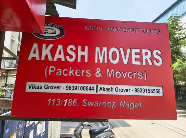 The Akash Movers signboard, showing the GSTIN, both contact numbers and the address at 113/186, Swaroop Nagar.